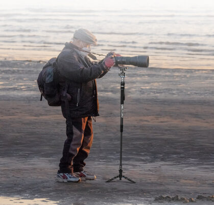 Fotograf som använder Sirui monopod SVM-165P (Pedal version) Rapid System på en strand