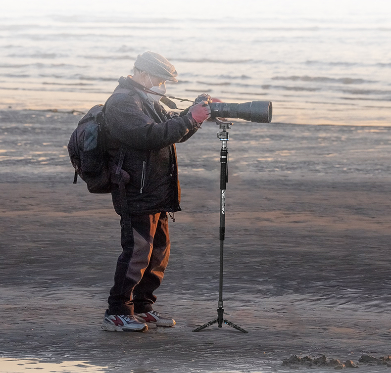 Fotograf som använder Sirui monopod SVM-165P (Pedal version) Rapid System på en strand