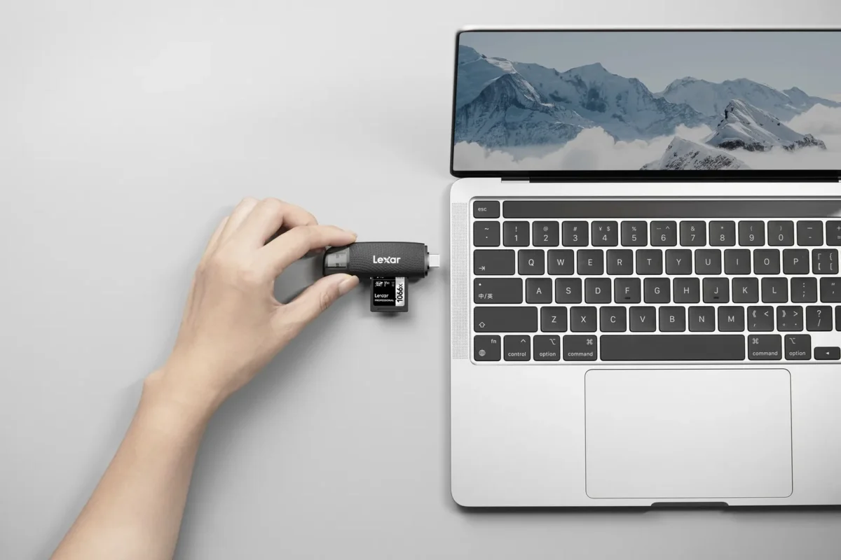 A hand plugging a card reader into a laptop