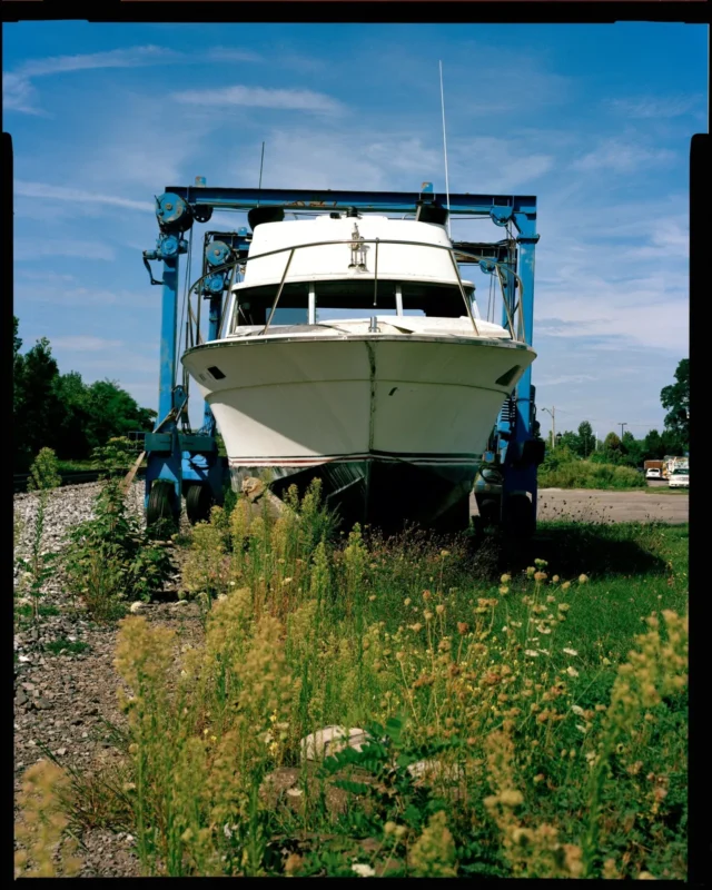 Colour film photo of a boat raised on a lift under a blue sky