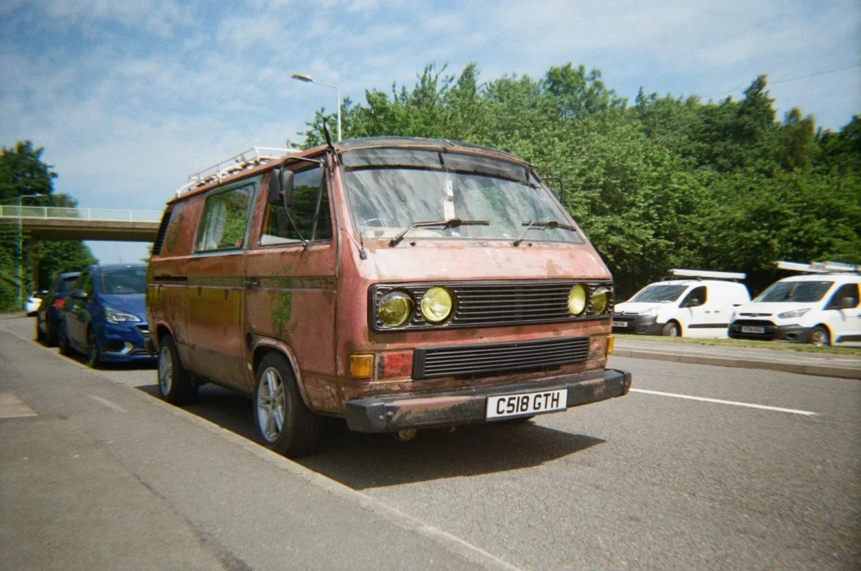 Colour film photo of a vintage VW bus on a sunny street