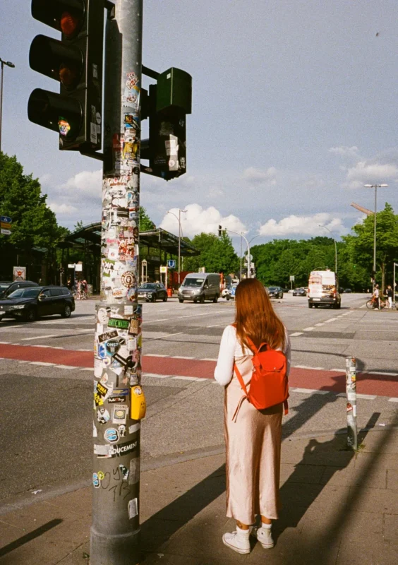 Colour film photo of a woman crossing a busy city street