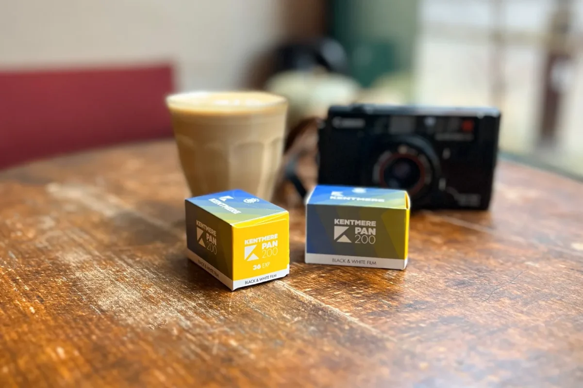 Film boxes beside a compact camera and a latte