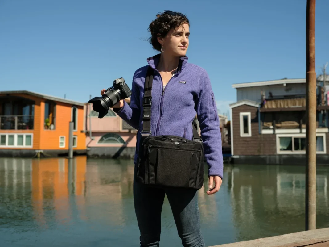 Photographer with a crossbody bag on a harbour boardwalk