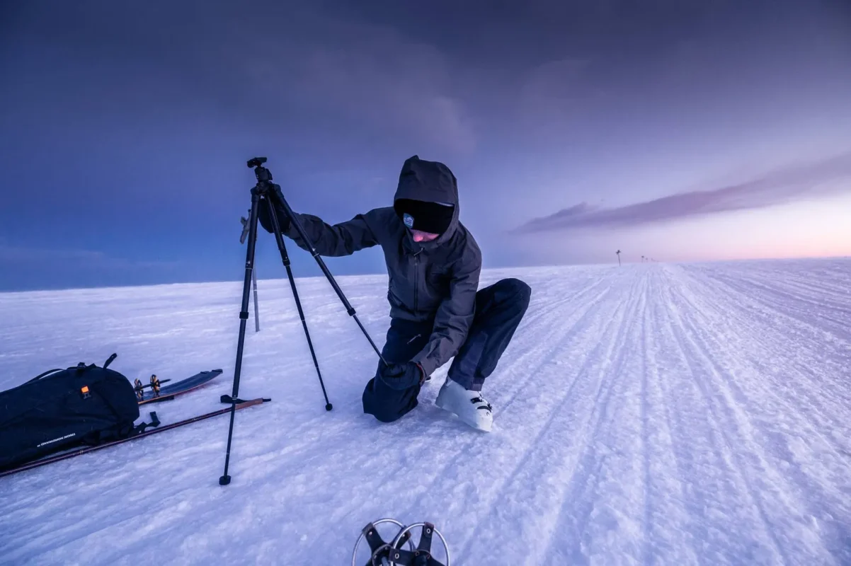 Photographer with a tripod on a snowy plain
