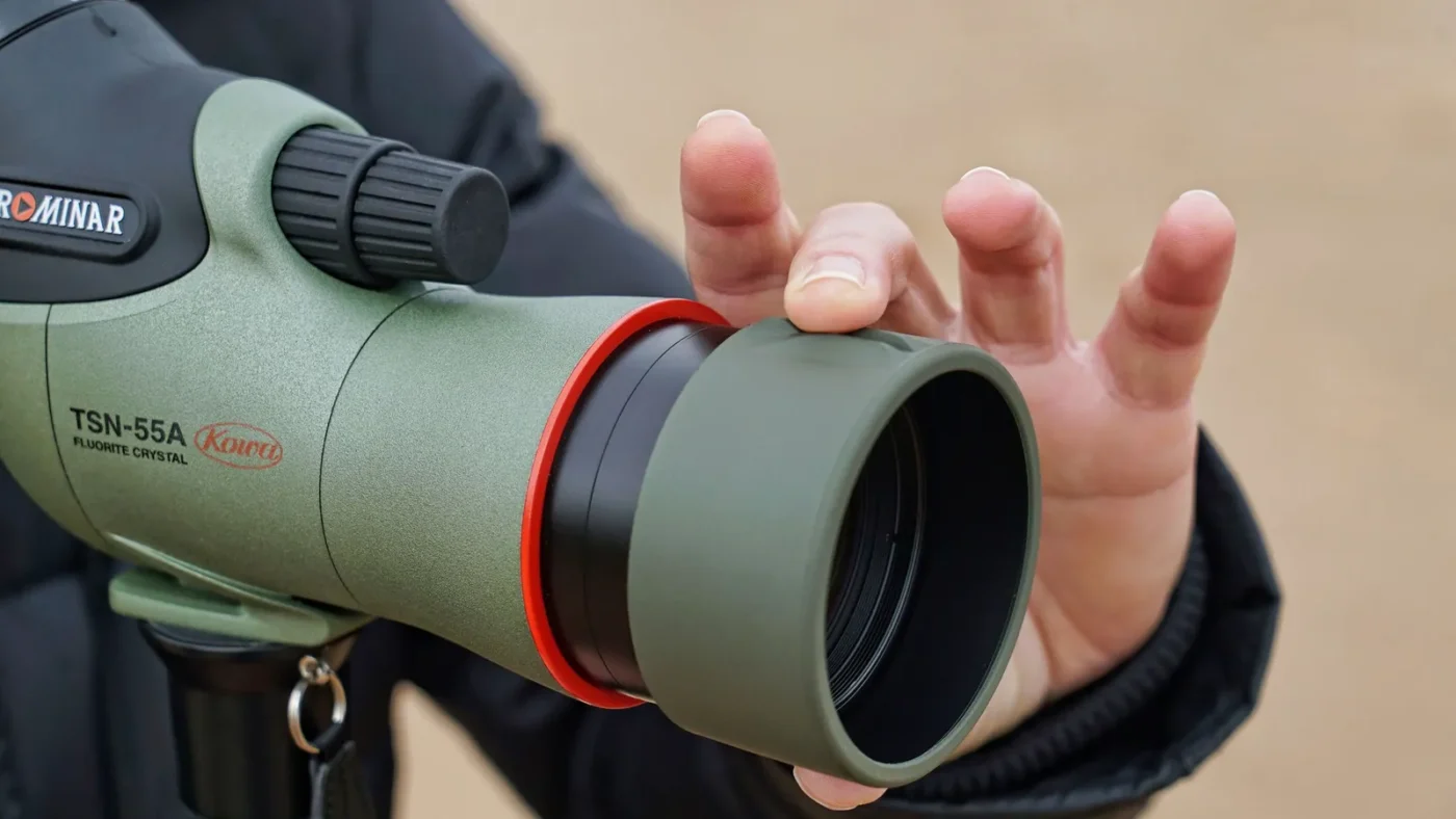 Hand on the eyepiece of a green spotting scope
