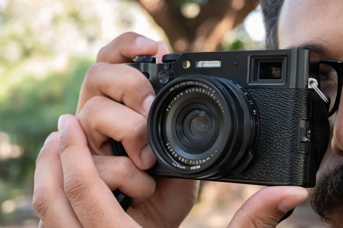 Hands holding a camera with a protective cover over the lens