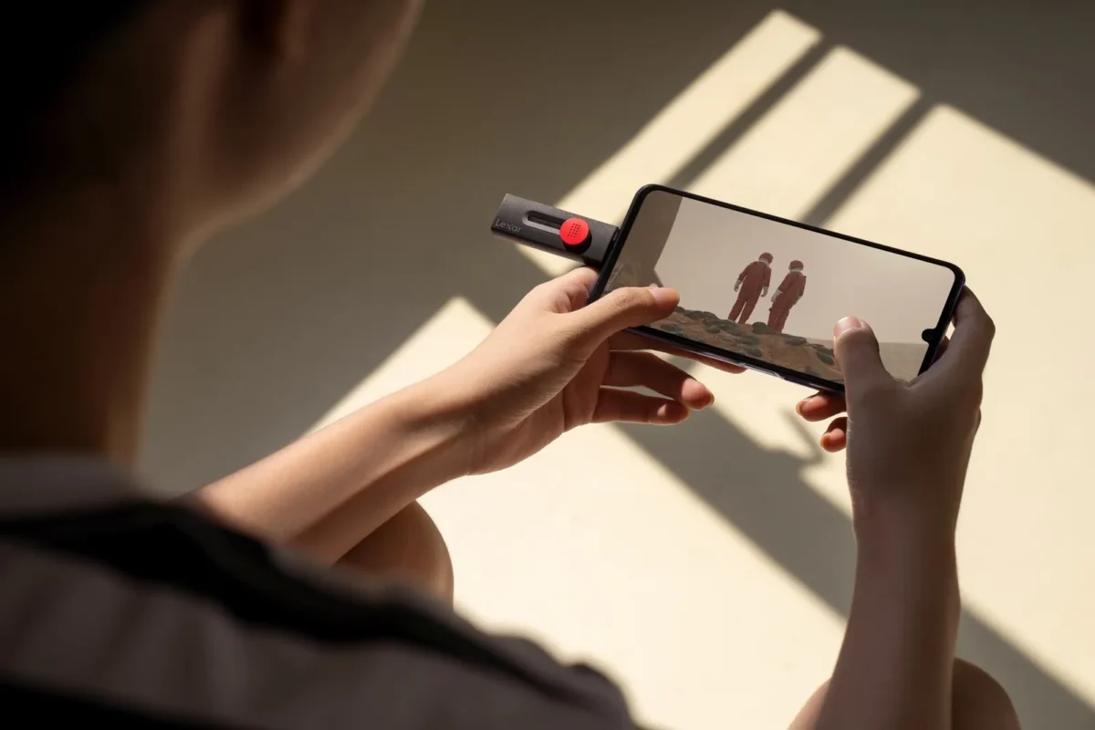 Hands holding a phone with a USB-C stick plugged in, in warm light