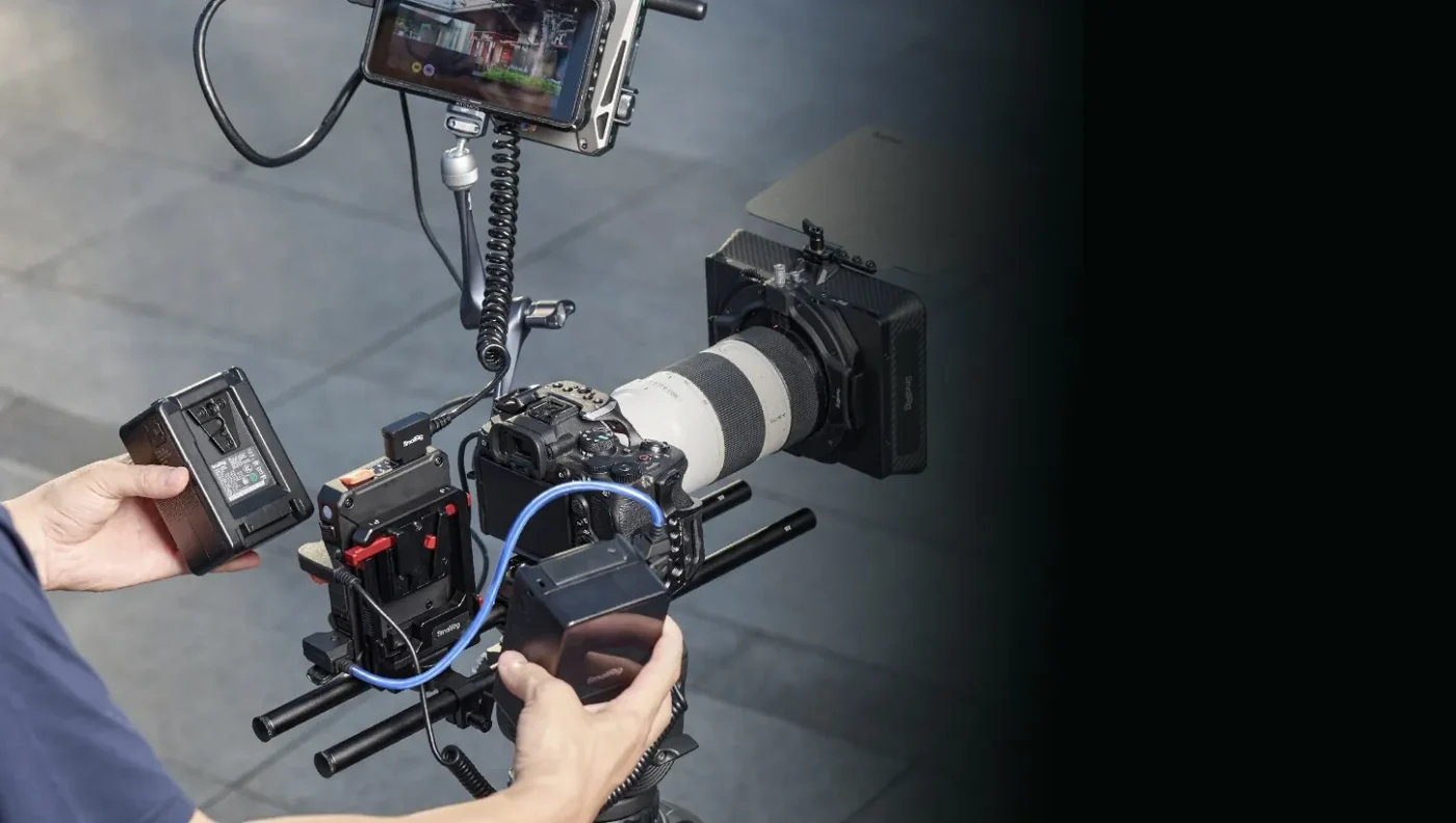 Hands connect cables on a cinema rig with a battery plate