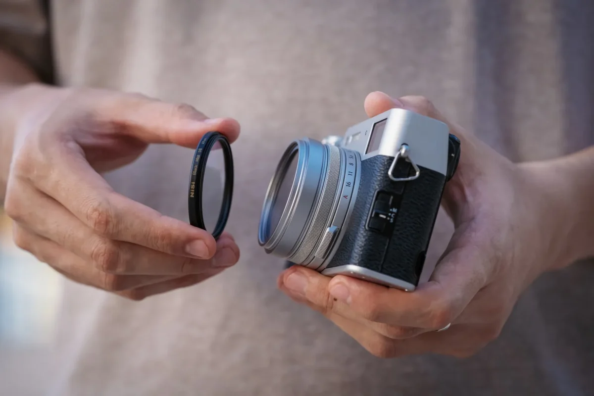 Hands fitting a protective ring to a silver compact camera