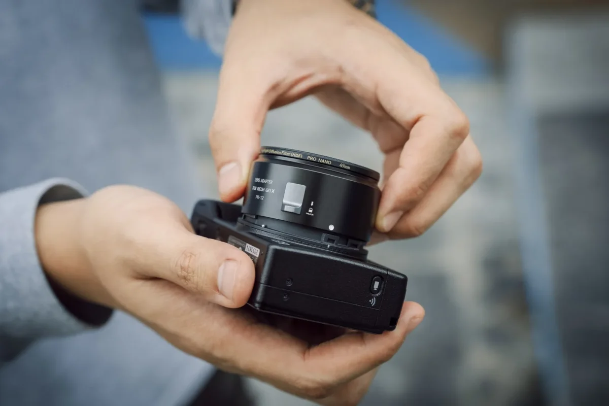 Hands mounting an adapted lens on a camera body