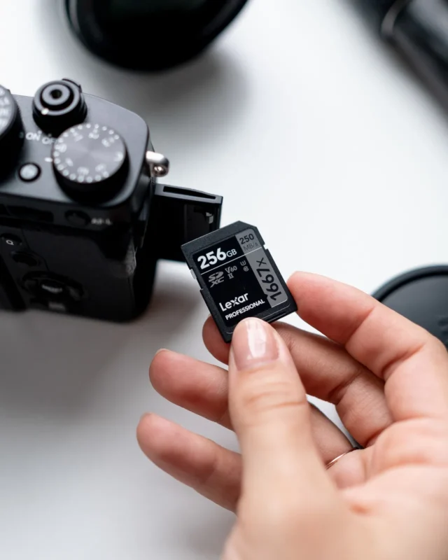 Hands inserting an SD card into a mirrorless camera