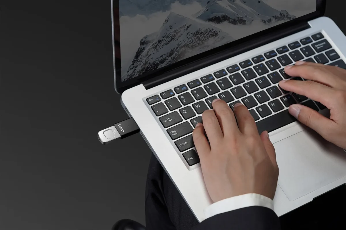 Hands typing on a laptop with a USB stick plugged in
