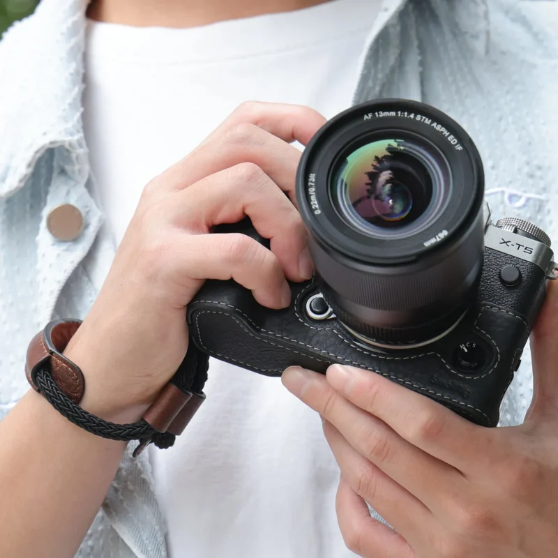 Hands holding a camera fitted with a shaped hand grip