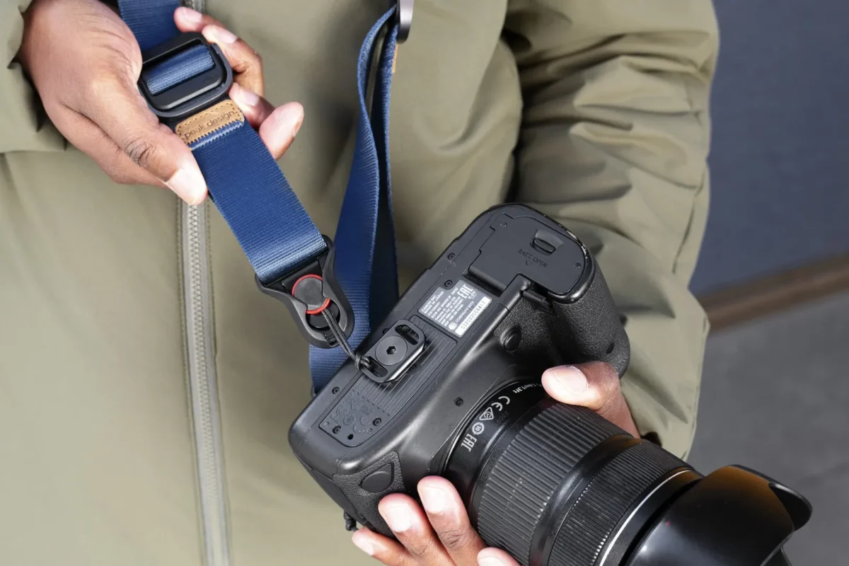 Hands adjusting a blue strap on a mirrorless camera