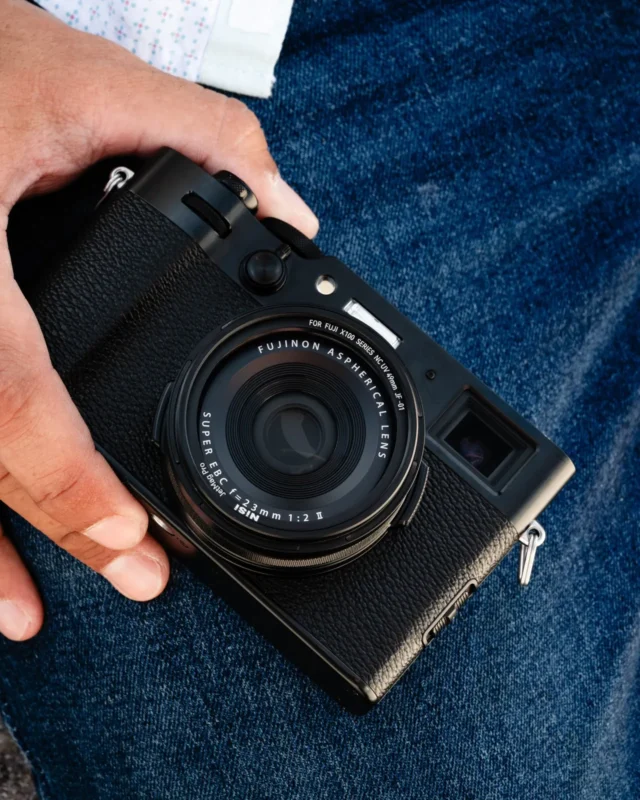 Compact camera with a lens hood held against denim