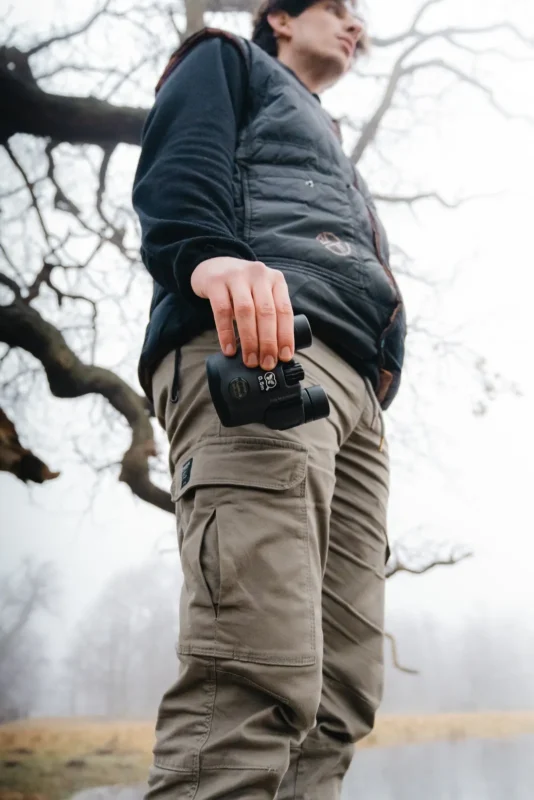 Compact binoculars in a case clipped to a hiker's trousers