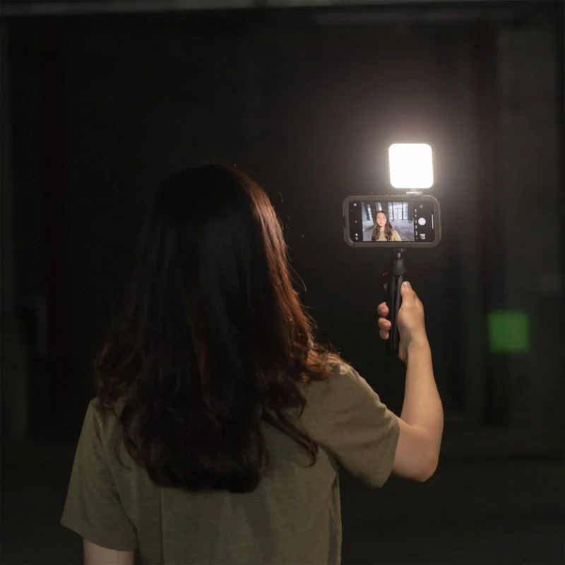 Woman filming herself with her phone and a small light attached to it