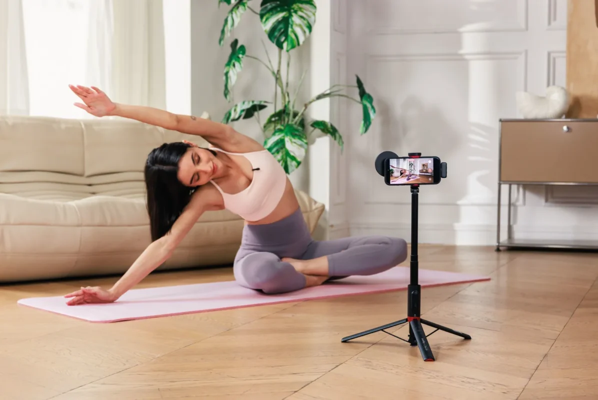 Woman films her yoga session with a phone on a tripod