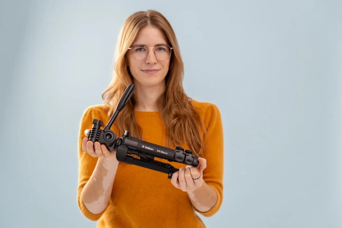 Woman in a mustard sweater holding up a compact tripod