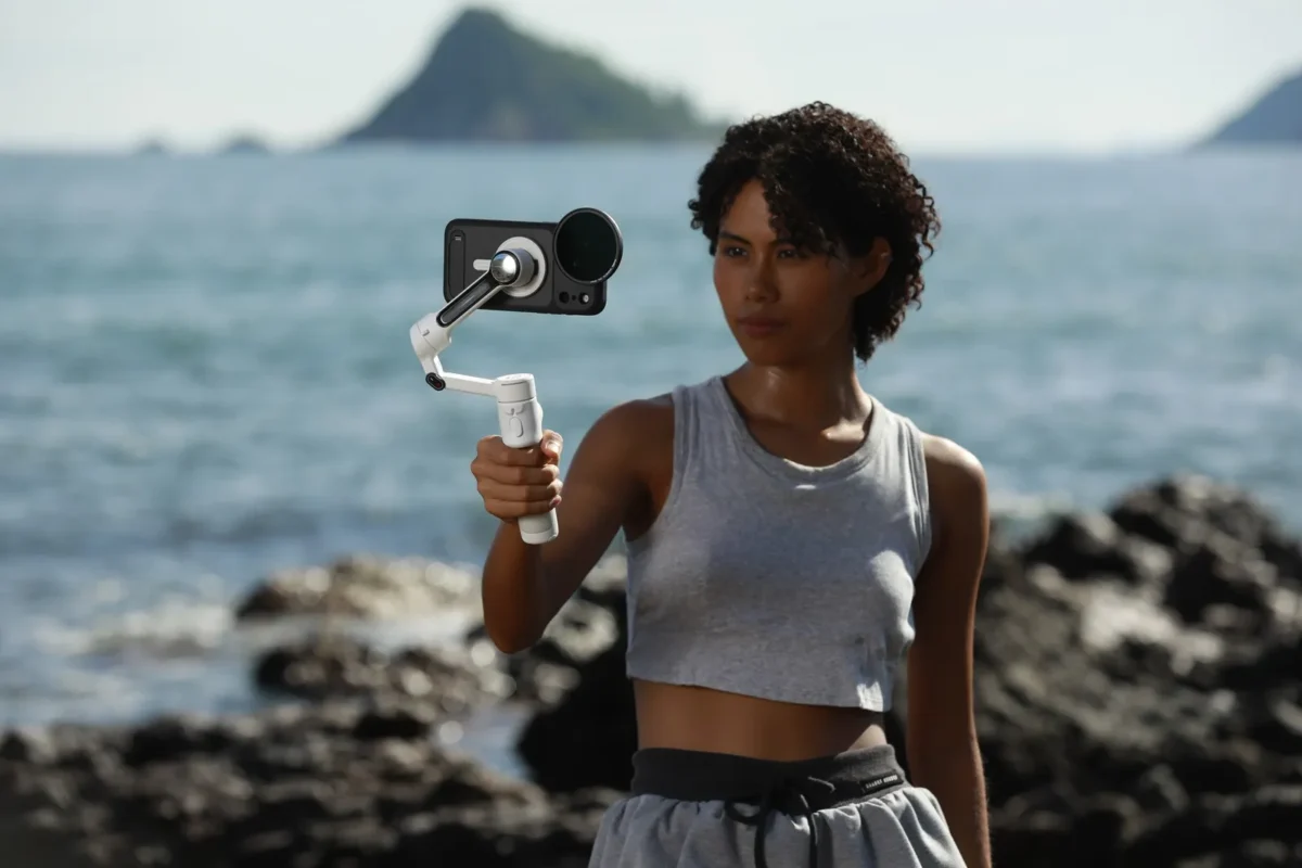 Woman on a coastal rock filming with a two-handled phone rig