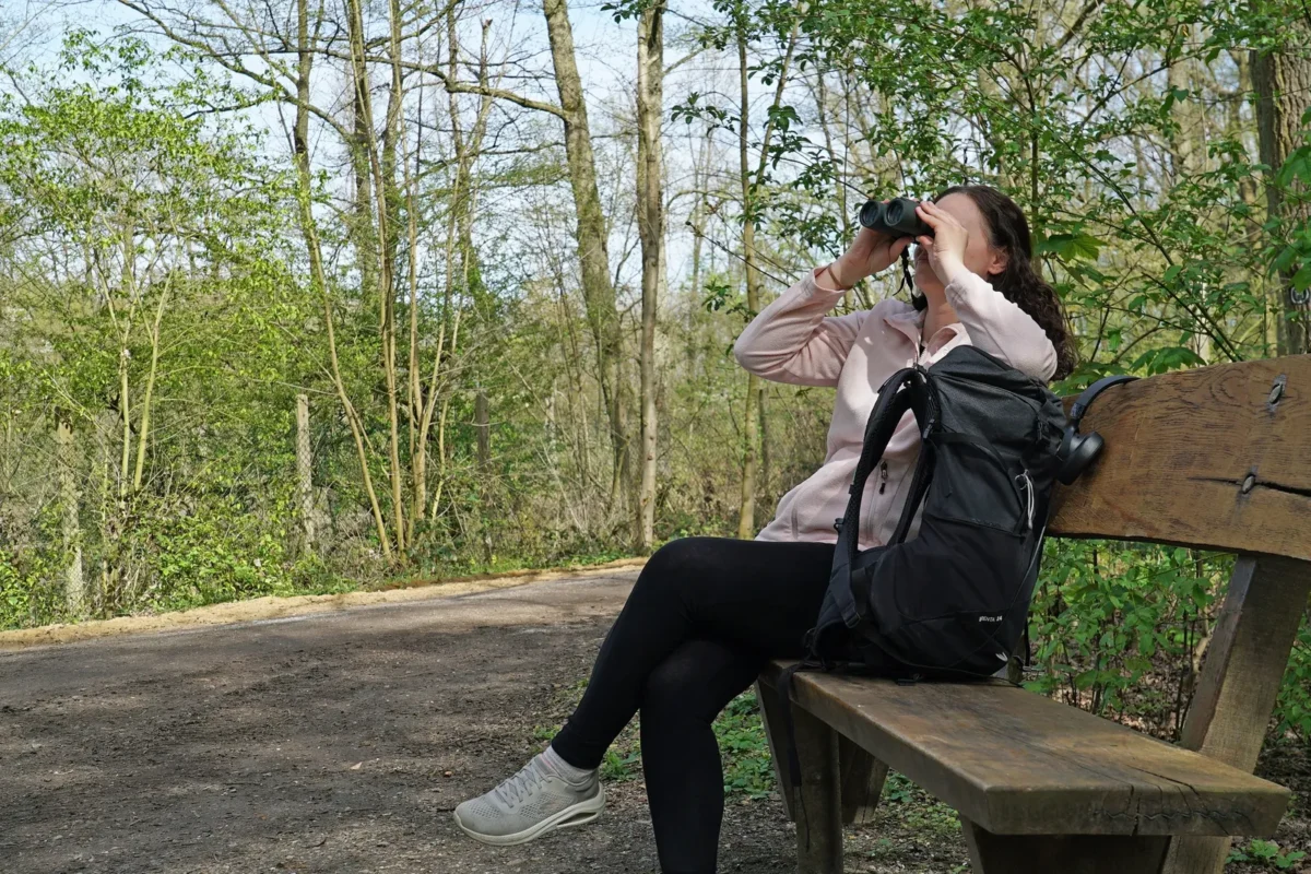 Woman on a park bench looking through compact binoculars