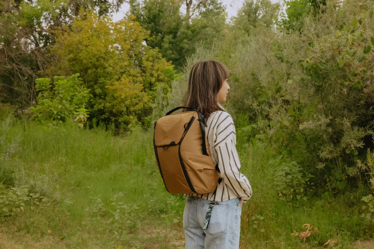 Woman in a summer meadow wearing a beige backpack