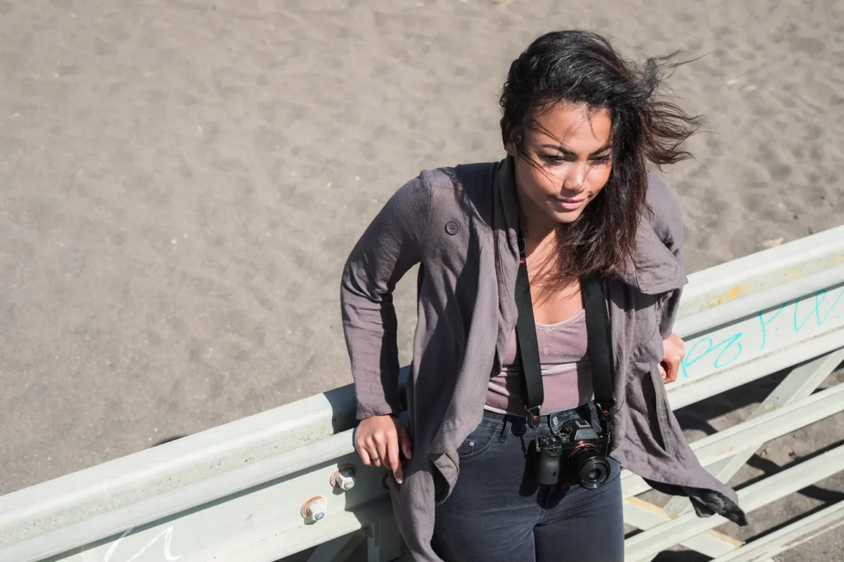 Woman on rocks with a camera hanging from a strap