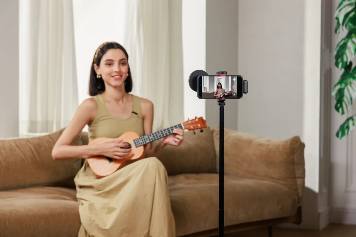 Woman playing a ukulele, filmed with a phone and a microphone