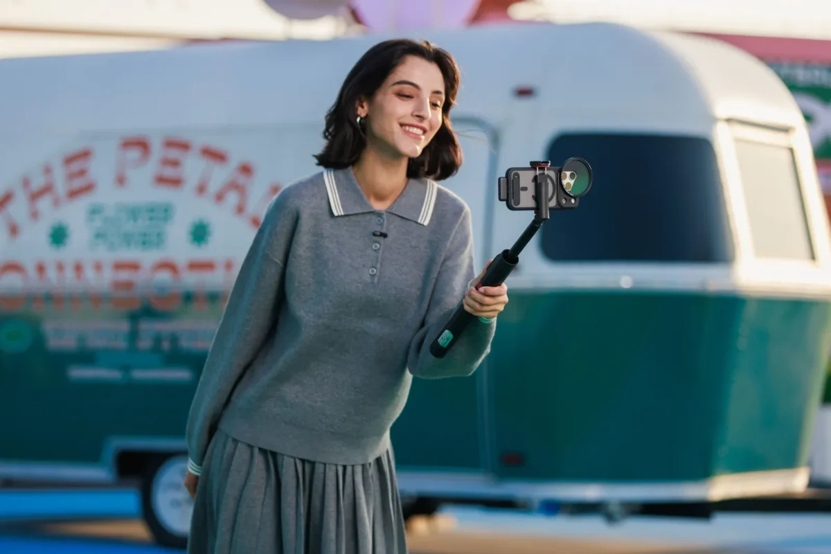 Woman vlogging by a vintage caravan with a microphone clipped to her top