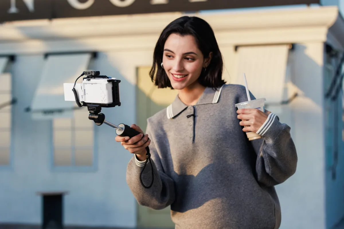 Smiling woman filming herself on the street with a phone rig and microphone