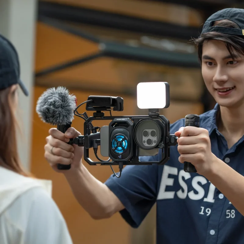 Smiling vlogger with a phone rig fitted with a microphone and a light