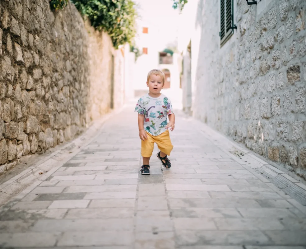 Toddler running down a sunlit alley