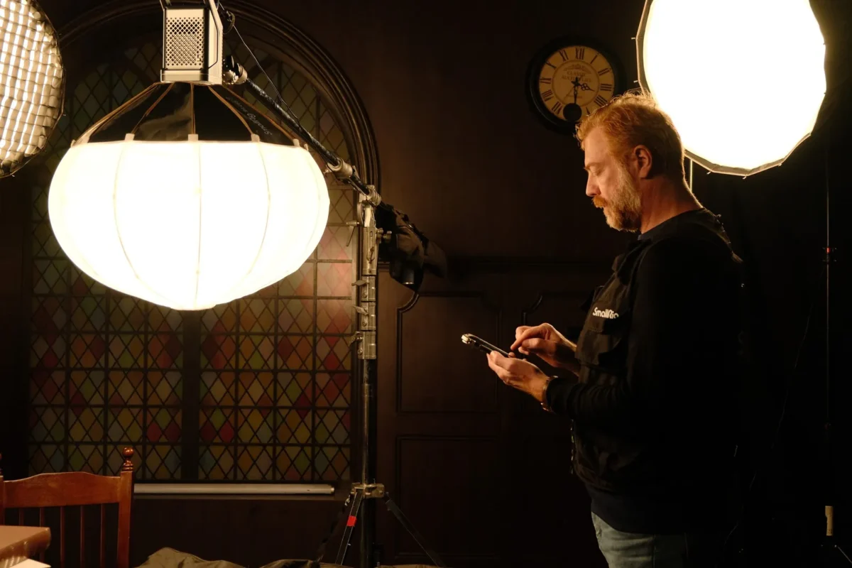 Gaffer rigging a lantern softbox over a warmly lit set