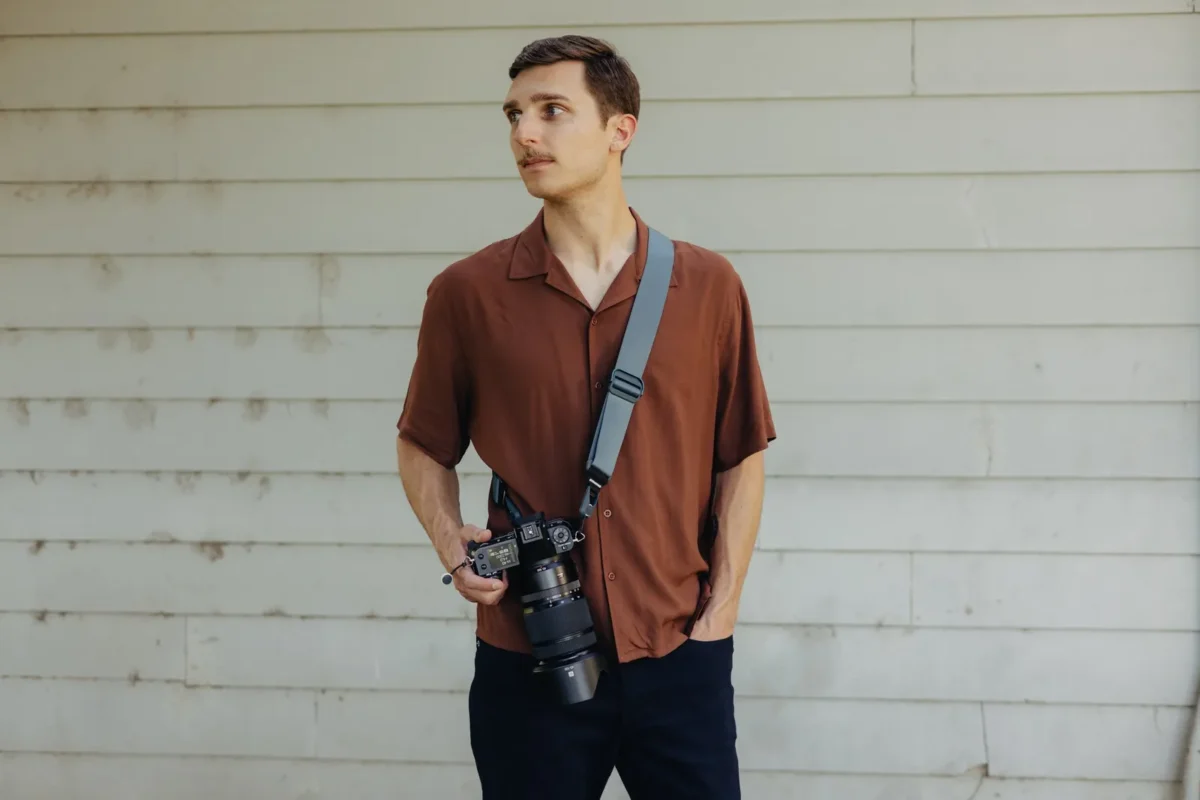 Man in a rust shirt with a camera on a shoulder strap