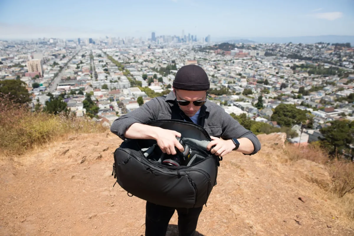 Man with a camera bag on a hilltop above the city
