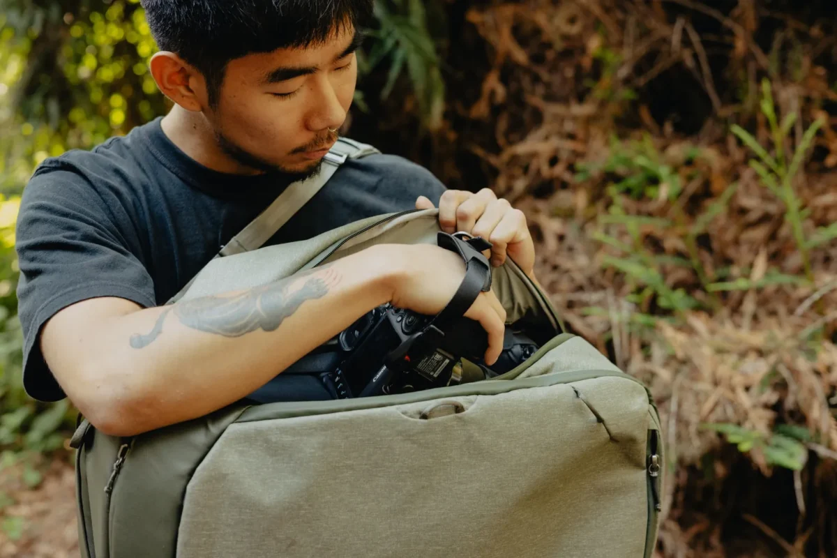 Man opening a camera bag outdoors to take out gear