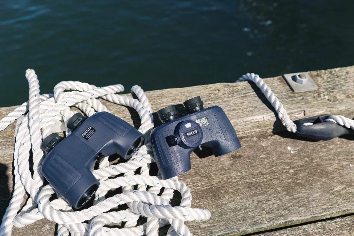 Marine binoculars on a weathered deck next to a rope