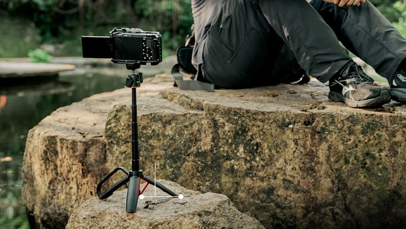 Mini tripod with a small camera on a rock outdoors