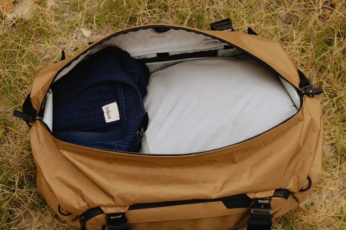 Open duffel bag packed with clothes on a sunny lawn