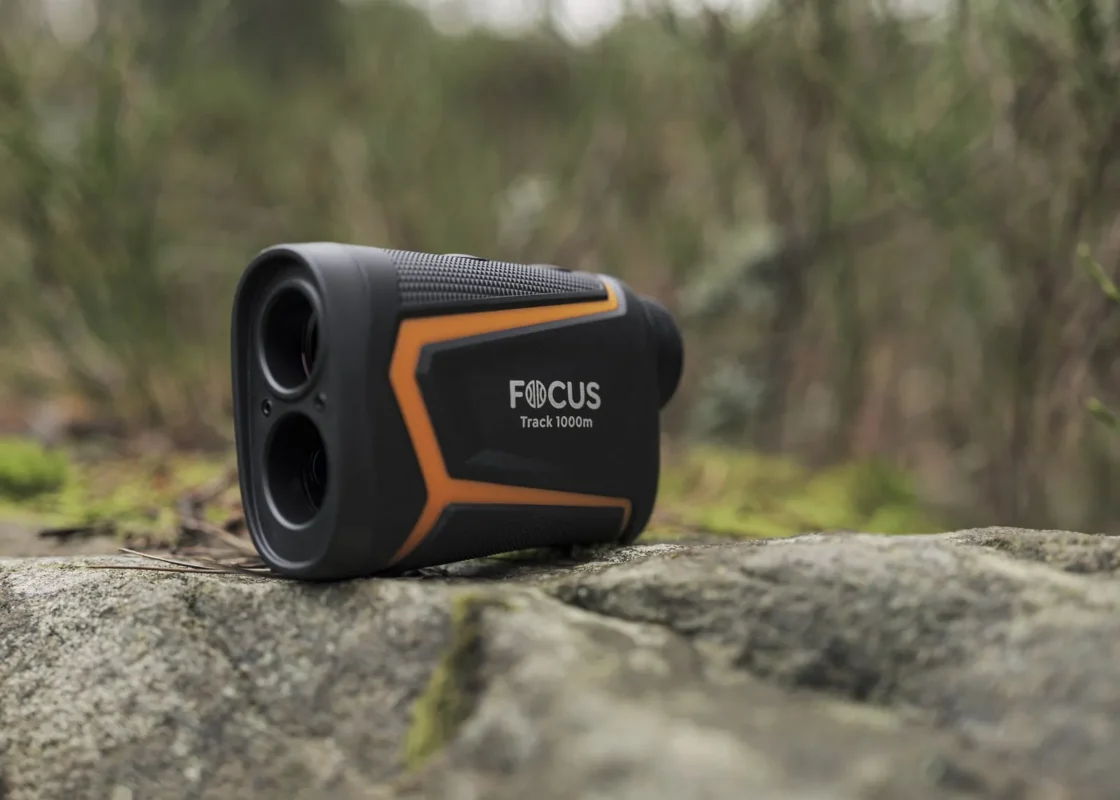Orange and black rangefinder on a mossy rock