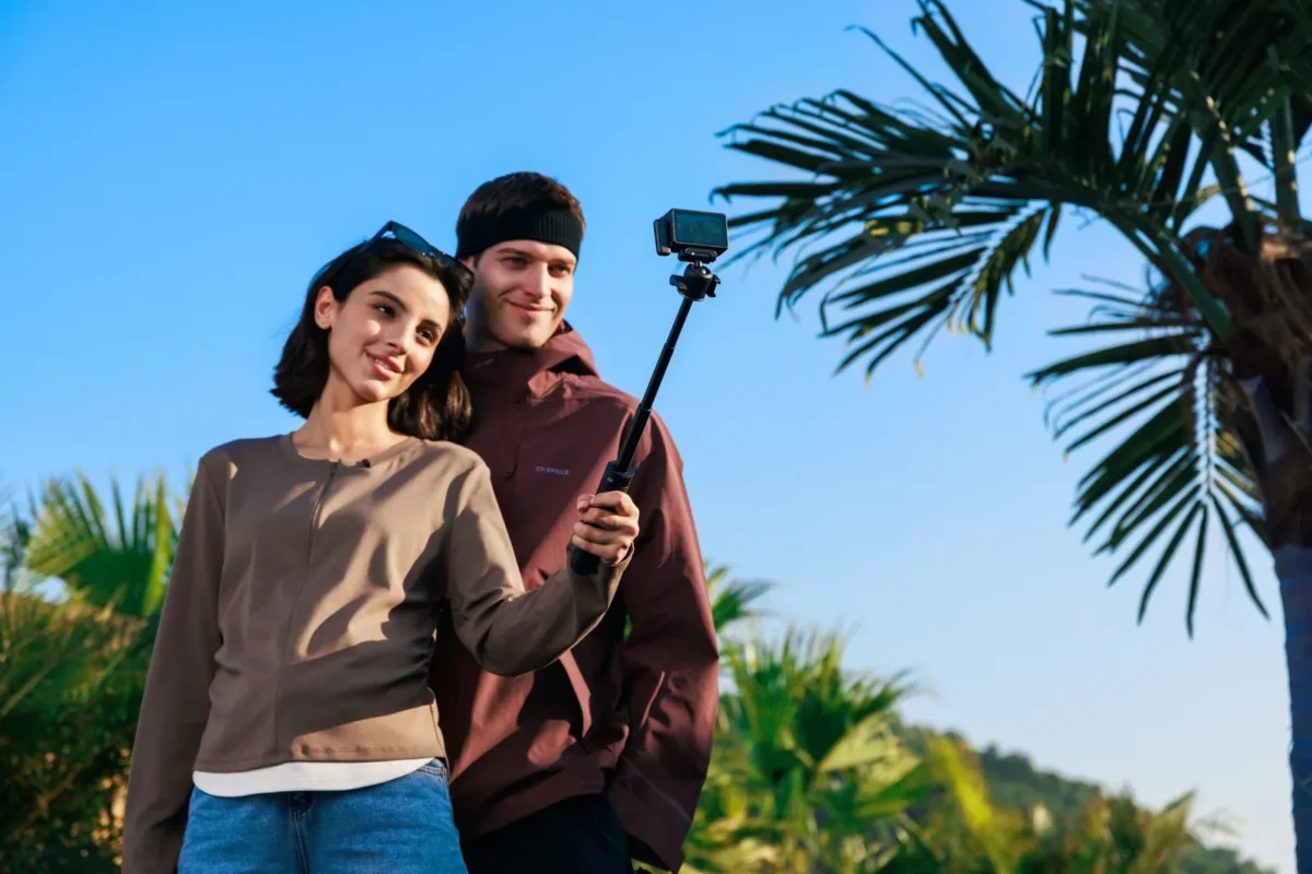 Couple vlogging with a selfie stick under palm trees