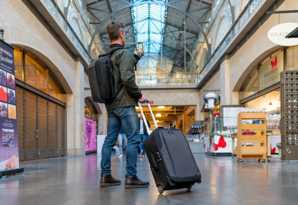 Traveller pulling a rolling camera bag through a station hall