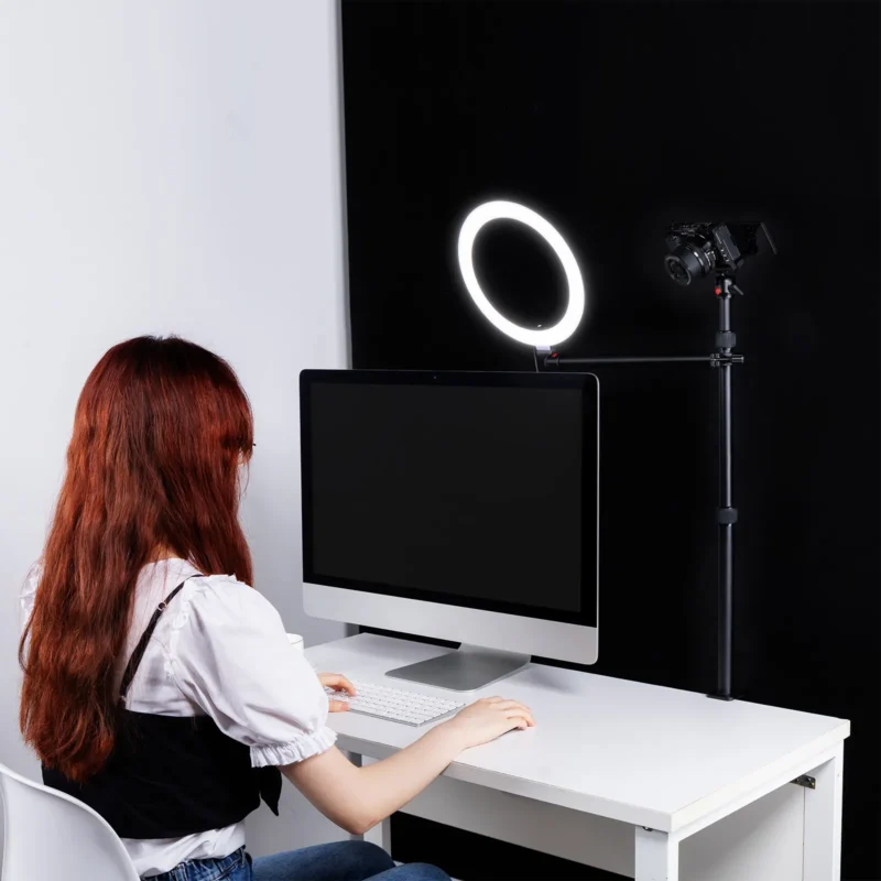 Desk with a ring light and a camera on an arm above the monitor