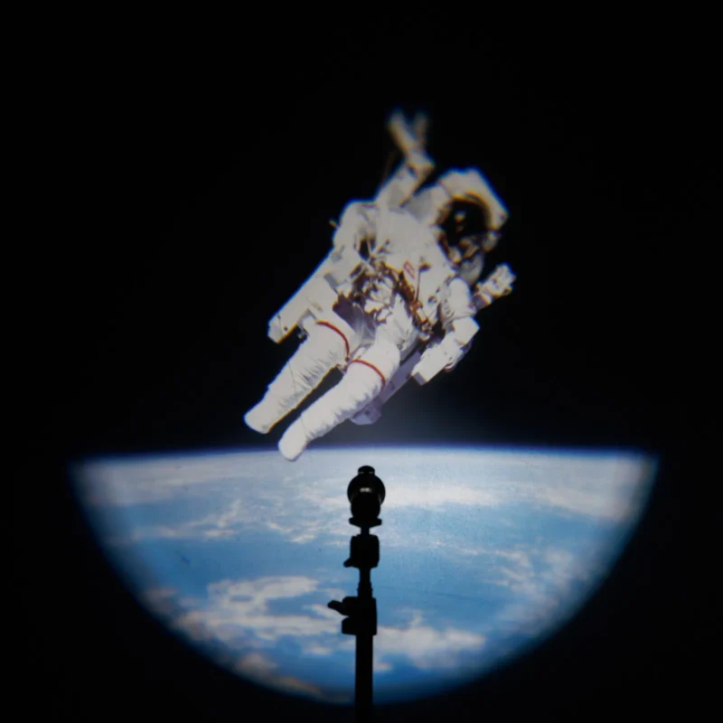 Spot light projecting an astronaut above the Earth onto a wall