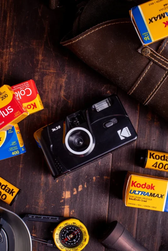 Black film camera with Kodak film rolls on a dark wooden table