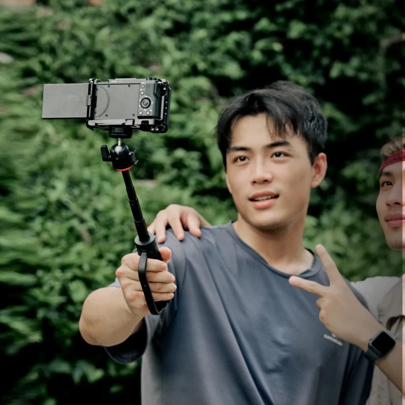 Young man vlogging with his phone on a stick with tripod legs