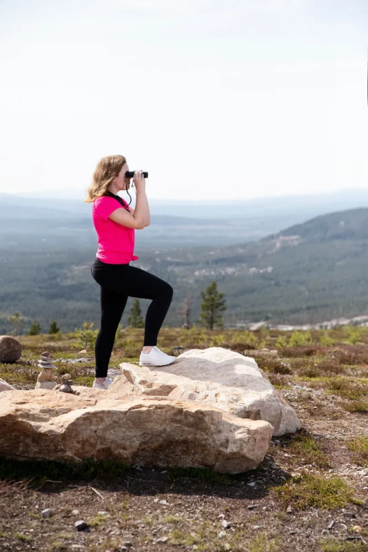 Hiker in pink scanning a valley from a rock