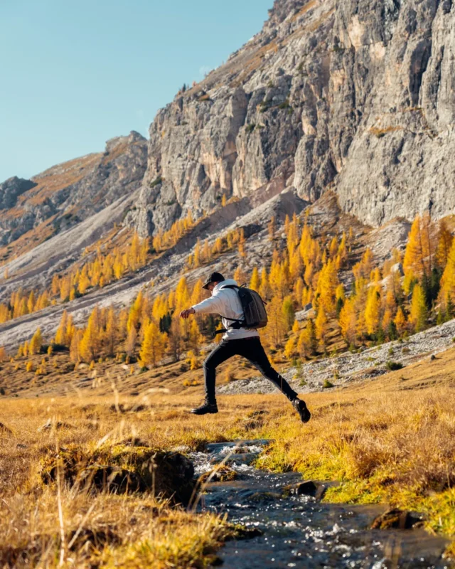 Hiker with a slim camera backpack in autumn mountains