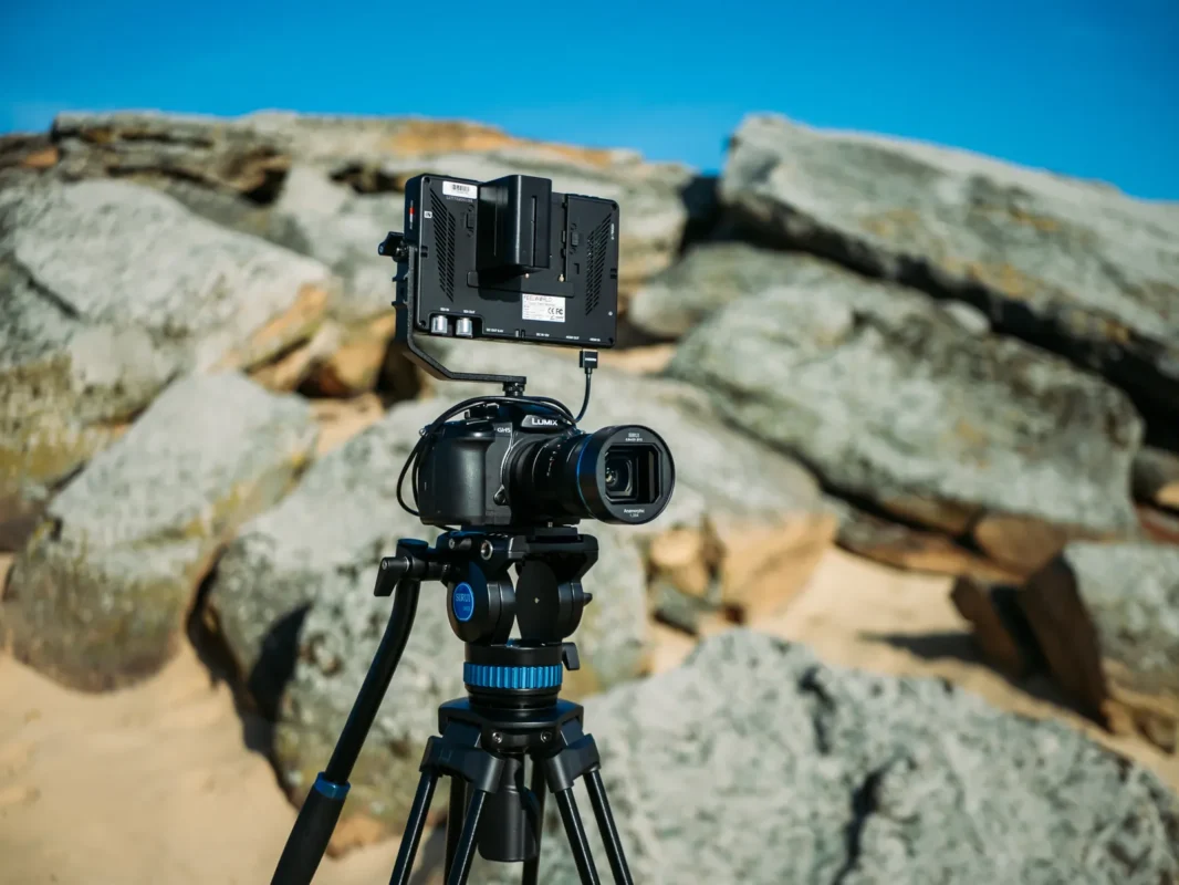 Video rig with a monitor on a tripod among coastal rocks